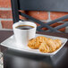 A 10 Strawberry Street bright white porcelain bistro cappuccino cup filled with coffee on a table with a plate of croissants.