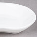A close up of a 10 Strawberry Street bright white elliptical porcelain plate with curved edges.