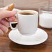 A hand holding a white 10 Strawberry Street espresso cup filled with coffee.