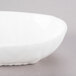 A 10 Strawberry Street bright white porcelain elliptical bowl with a curved edge on a gray surface.
