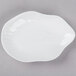 A white porcelain dish with an irregular oval shape on a gray surface.