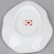 A bright white porcelain dish with an irregular oval shape and a red logo on it.