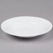 A white bowl with a wide rim on a gray background.