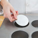 A hand putting a Chicago Metallic mini-cheesecake disk in a muffin pan.
