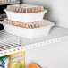 A white True Coated Wire Shelf with food in containers on it.