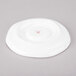 A bright white porcelain saucer with a rippled edge.