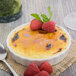 A 10 Strawberry Street white porcelain fluted creme brulee dish with creme brulee, raspberries, and mint leaves.