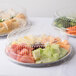 A Durable Packaging round catering tray filled with plastic food containers with different types of food.