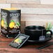 A black bowl with a Steep By Bigelow Chamomile Citrus tea bag in it next to a box of Steep By Bigelow Organic Chamomile Citrus tea.