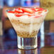 A Libbey martini glass filled with yogurt topped with strawberries and granola.