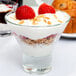 A Libbey martini glass filled with a dessert with yogurt, strawberries, and oat flakes.