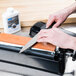 A person using a Dexter-Russell Tri-Stone knife sharpener to sharpen a knife.