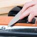 A person's hand using a Dexter-Russell manual knife sharpener.