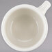 A Tuxton eggshell white china cup with a handle.