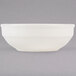 A Tuxton eggshell china bowl with a white rim on a gray background.