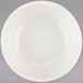 A white Tuxton china bowl with a white rim on a gray surface.