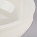 A close up of a Tuxton eggshell china bowl with a circular rim.