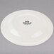 A white Tuxton Reno china plate with black text reading "Tuxton" on the rim.