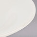 A close up of a Tuxton eggshell china bowl with a white rim.
