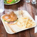 A TreeVive by EcoChoice compostable palm leaf plate with a sandwich on a table.