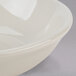 A Tuxton eggshell white china fruit bowl with a rim.