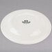A Tuxton Reno ivory china plate with black text that says "Tuxton" in black.