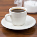 A Tuxton Reno espresso saucer with a cup of coffee on it.