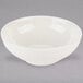 A Tuxton Eggshell China bowl with a small rim on a gray background.