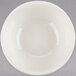 A white Tuxton nappie bowl with a white rim on a gray surface.