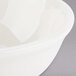 A Tuxton eggshell china bowl with a white rim.