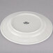 A Tuxton Reno eggshell china plate with a wide rim and black text on it.