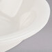 A close up of a Tuxton eggshell white china fruit bowl with a curved edge.