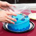 A person using a D&W Fine Pack plastic lid to cover a cake.