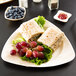 A TreeVive by EcoChoice triangular palm leaf plate with food on it.