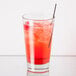 A Libbey rim tempered mixing glass with a red drink, ice, and a straw.