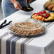 A clear Visions round catering tray with cookies and fruit on a table.