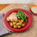 A Carlisle red melamine plate with chicken, potatoes, and green beans.