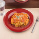 A red Carlisle Sierrus melamine plate with spaghetti, bread, and a fork on it.