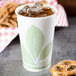 A Bare by Solo wax treated paper cold cup with ice in it on a table with pretzels.