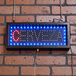 An Aarco Cerveza beer LED sign with blue lights on a brick wall.