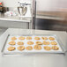 A Vollrath Wear-Ever bun pan filled with cookies on a kitchen counter.
