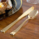 A plate of food with a Fineline gold plastic spoon on a table.