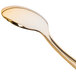 A close up of a Fineline gold plastic spoon with a white background.