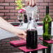 A person pouring wine into a Fineline clear plastic carafe.