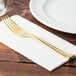 A Fineline heavy weight gold plastic fork on a napkin.