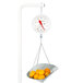 A Cardinal Detecto hanging scale with a basket of oranges on a table.