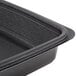 A black Genpak rectangular microwaveable container with a lid on a counter.
