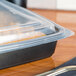 A Genpak black plastic rectangular microwaveable container with food in it.