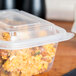A Genpak clear plastic rectangular lid on a plastic container with food inside.