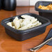Two black Genpak rectangular microwaveable containers filled with pasta on a table.